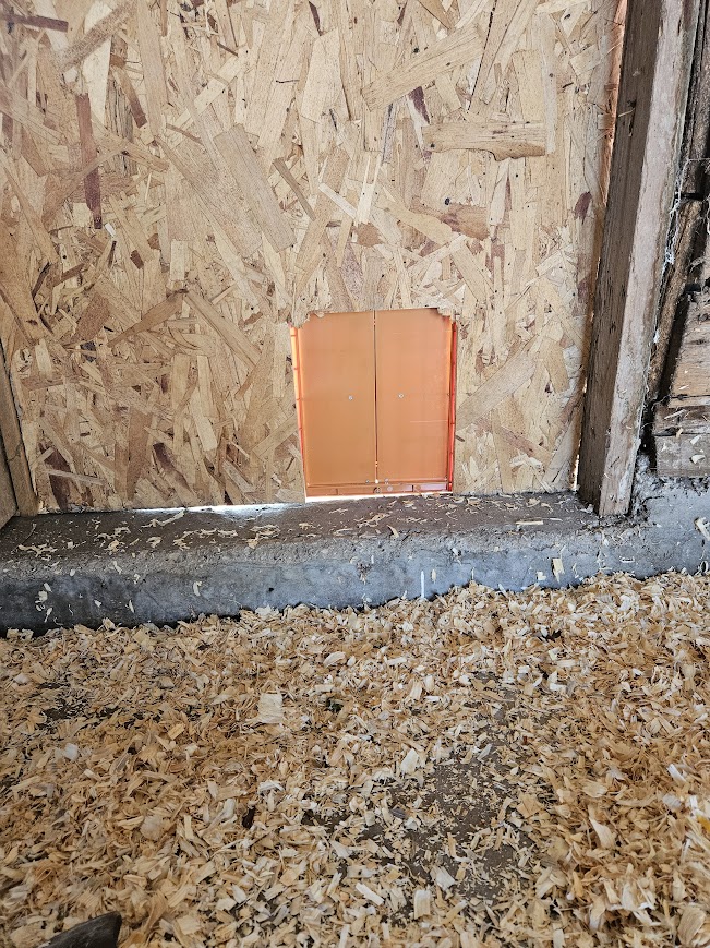 A closed chicken coop door on a wooden wall